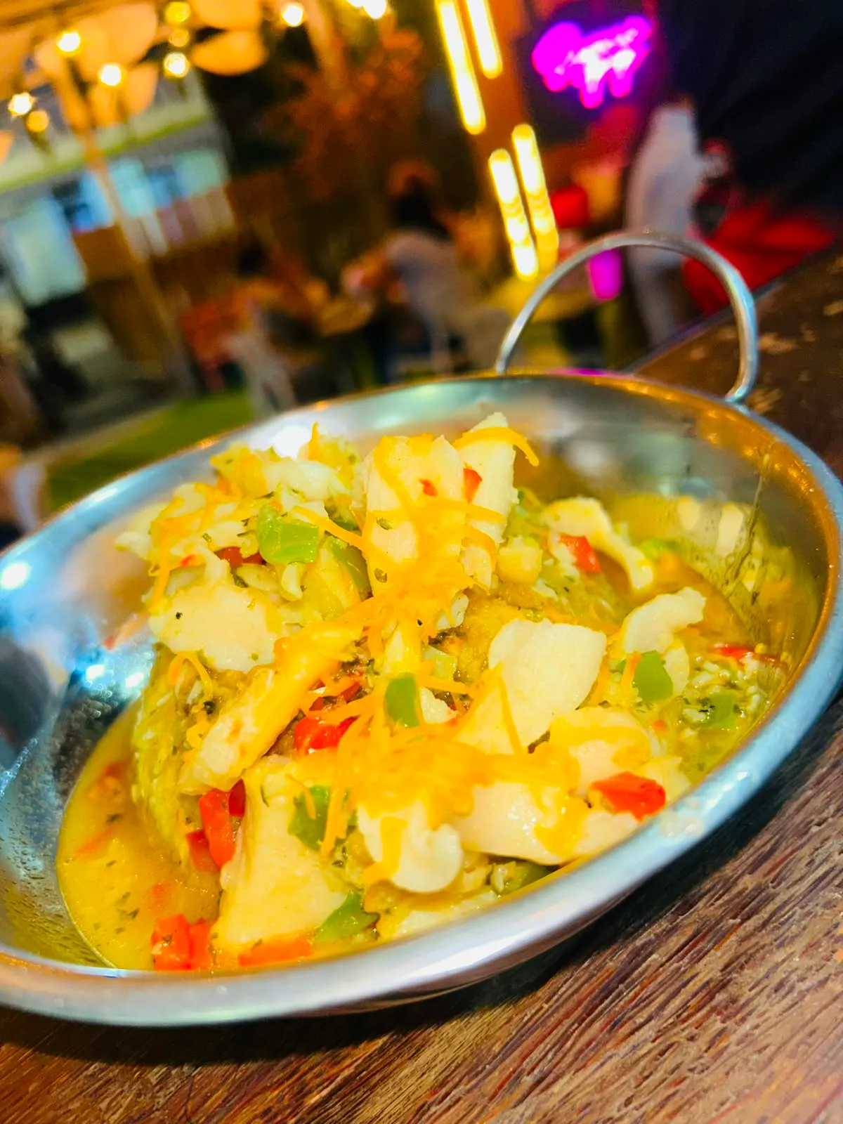 Cazuela metálica con pescado y vegetales en salsa cremosa con queso.