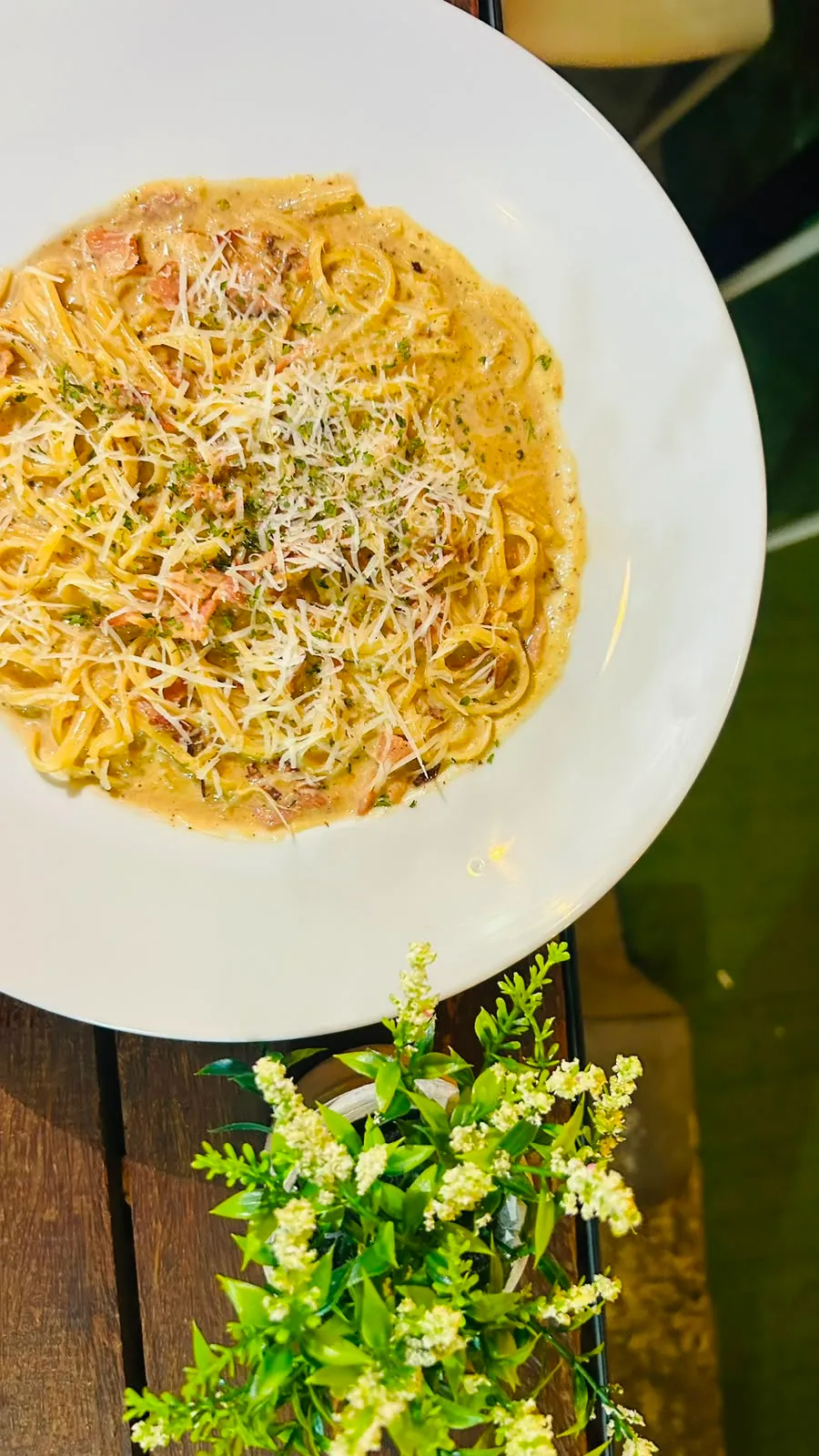 Plato de pasta carbonara con tocineta y queso parmesano.
