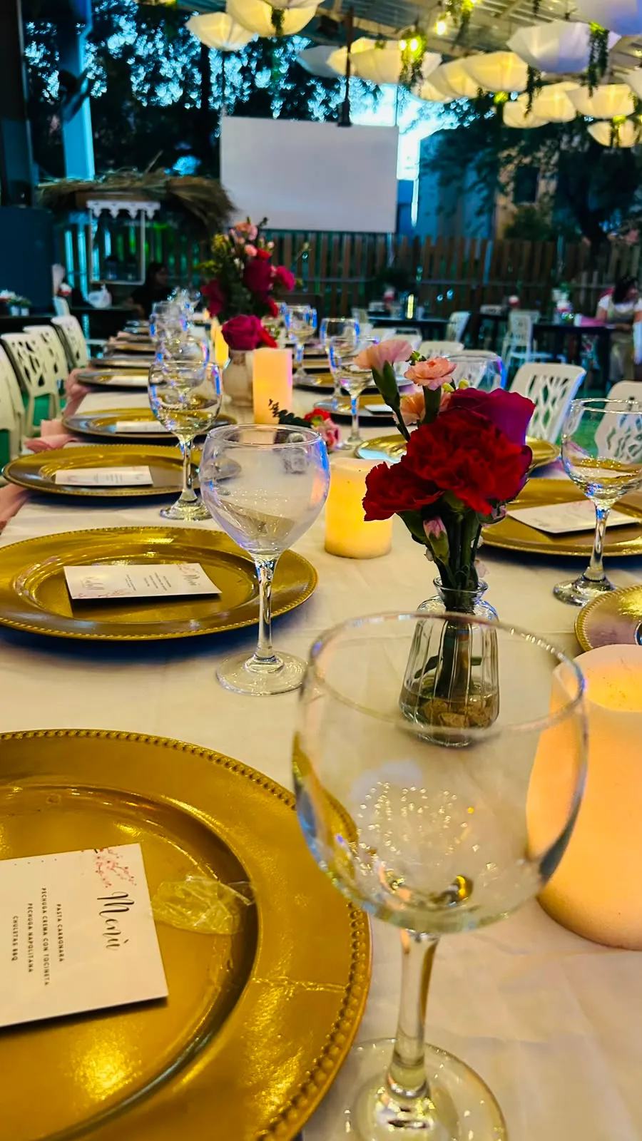 Montaje elegante con platos base dorados, rosas rojas y velas.