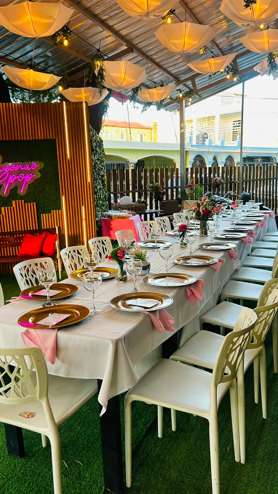 Mesa de banquete con el letrero neón de Sazonao Pop al fondo.