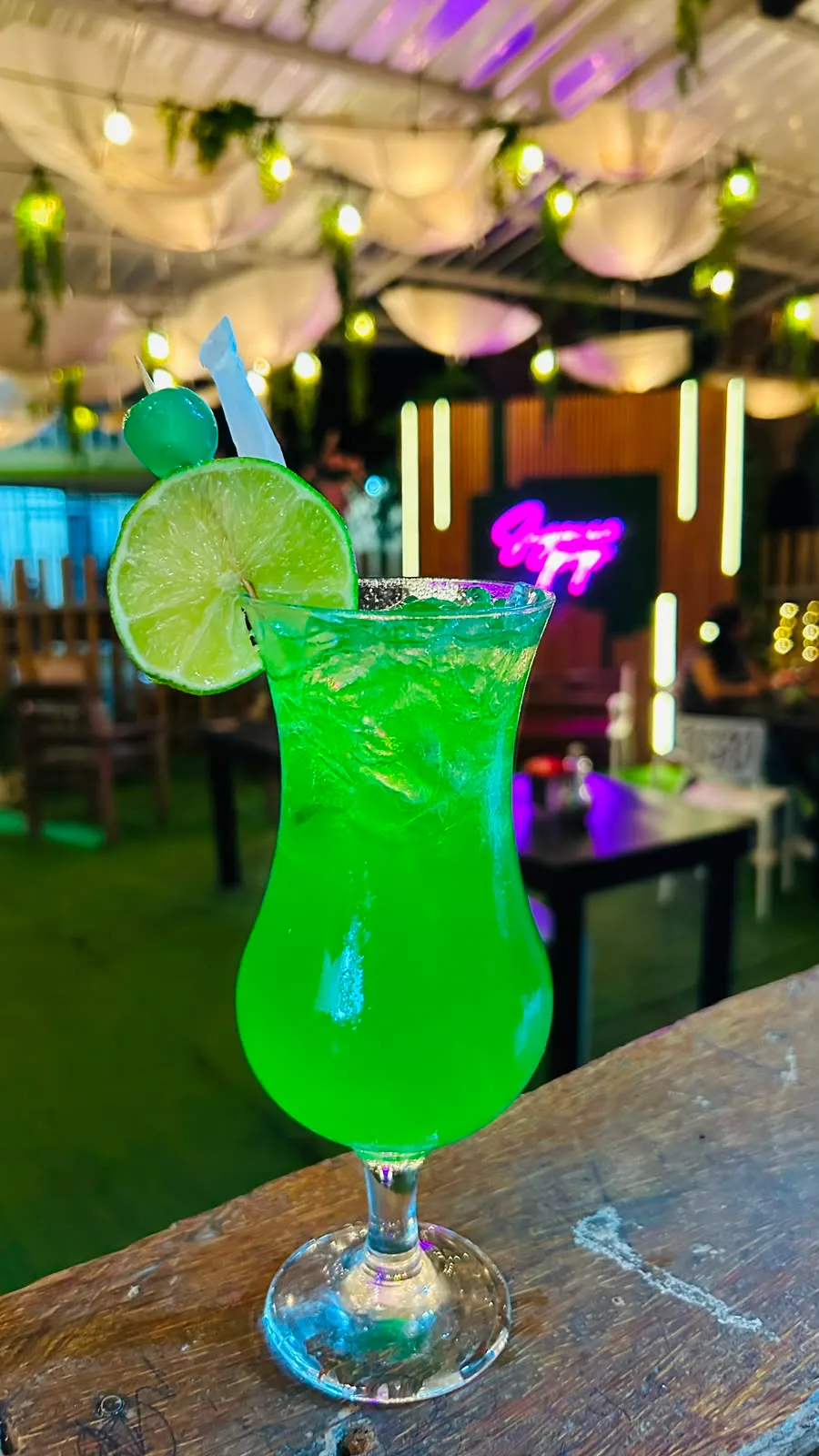 Cóctel tropical de color verde brillante con limón y cereza.