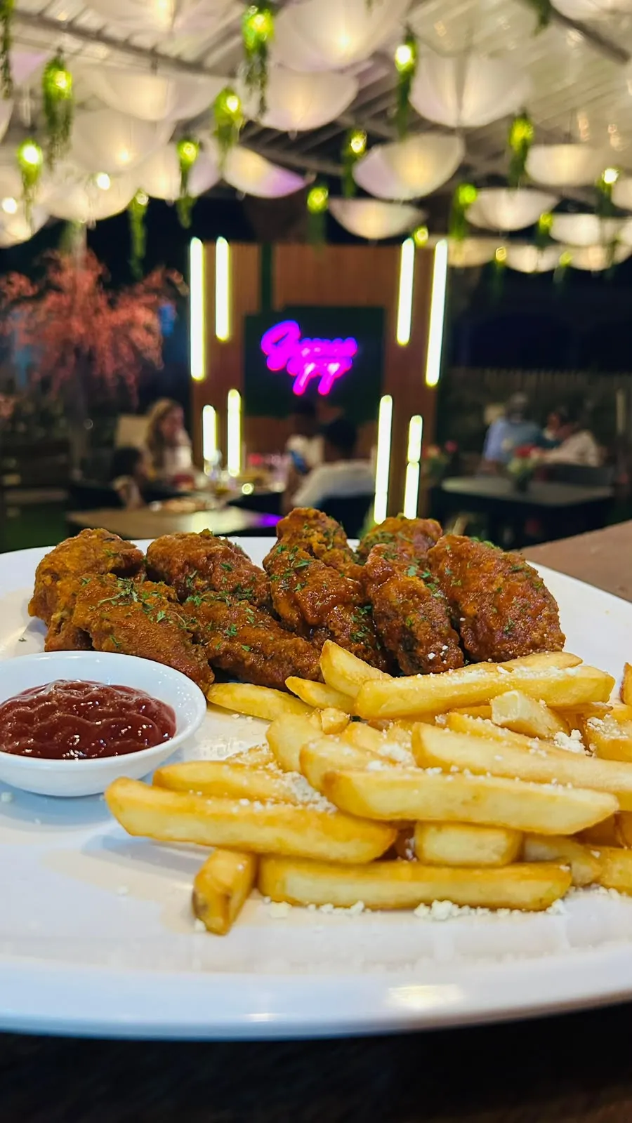 Alitas de pollo glaseadas con papas fritas espolvoreadas con queso.
