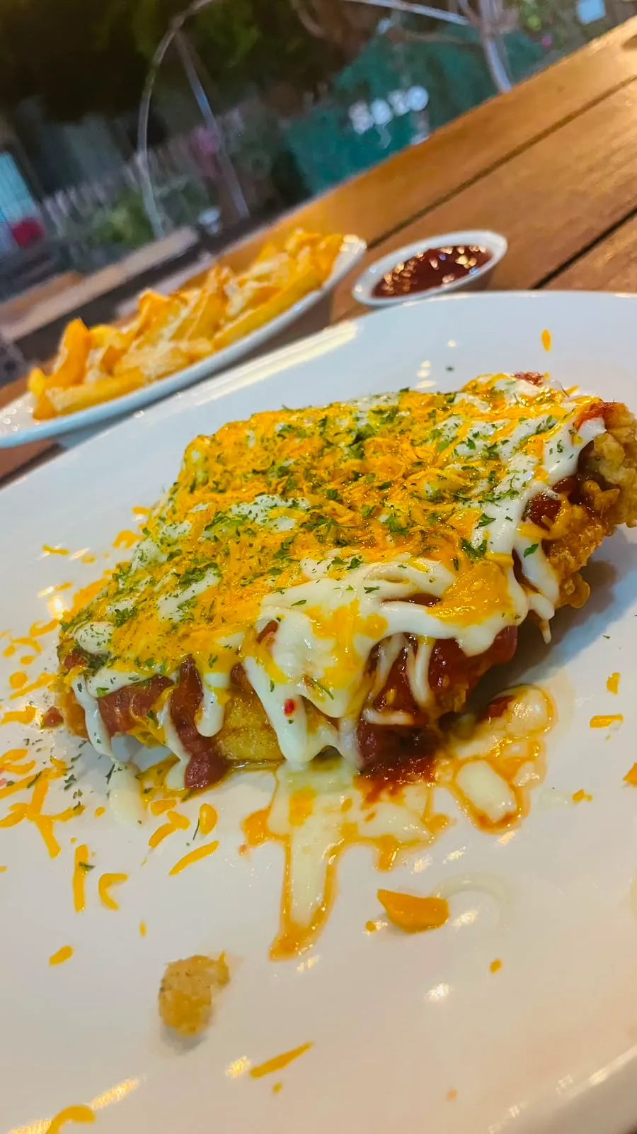 Milanesa dorada gratinada con queso derretido y hierbas, con papas fritas.